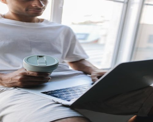 Indonesian man taking a short break from laptop, looking out the window